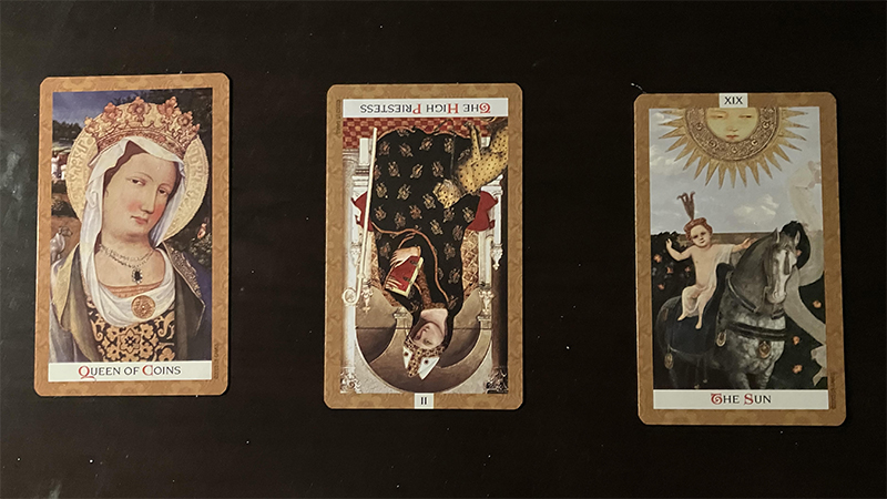 The Queen of Coins, the High Priestess reversed, and the Sun.